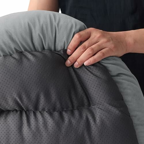 Hand drückt auf graues Kissen